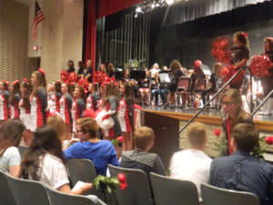 The 2016-2017 student council sits in the foreground as cheerleaders accompany the band while students enter the assembly
